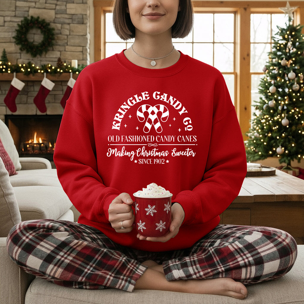 Person wearing a red sweater with Christmas-themed text, sitting in a cozy living room.