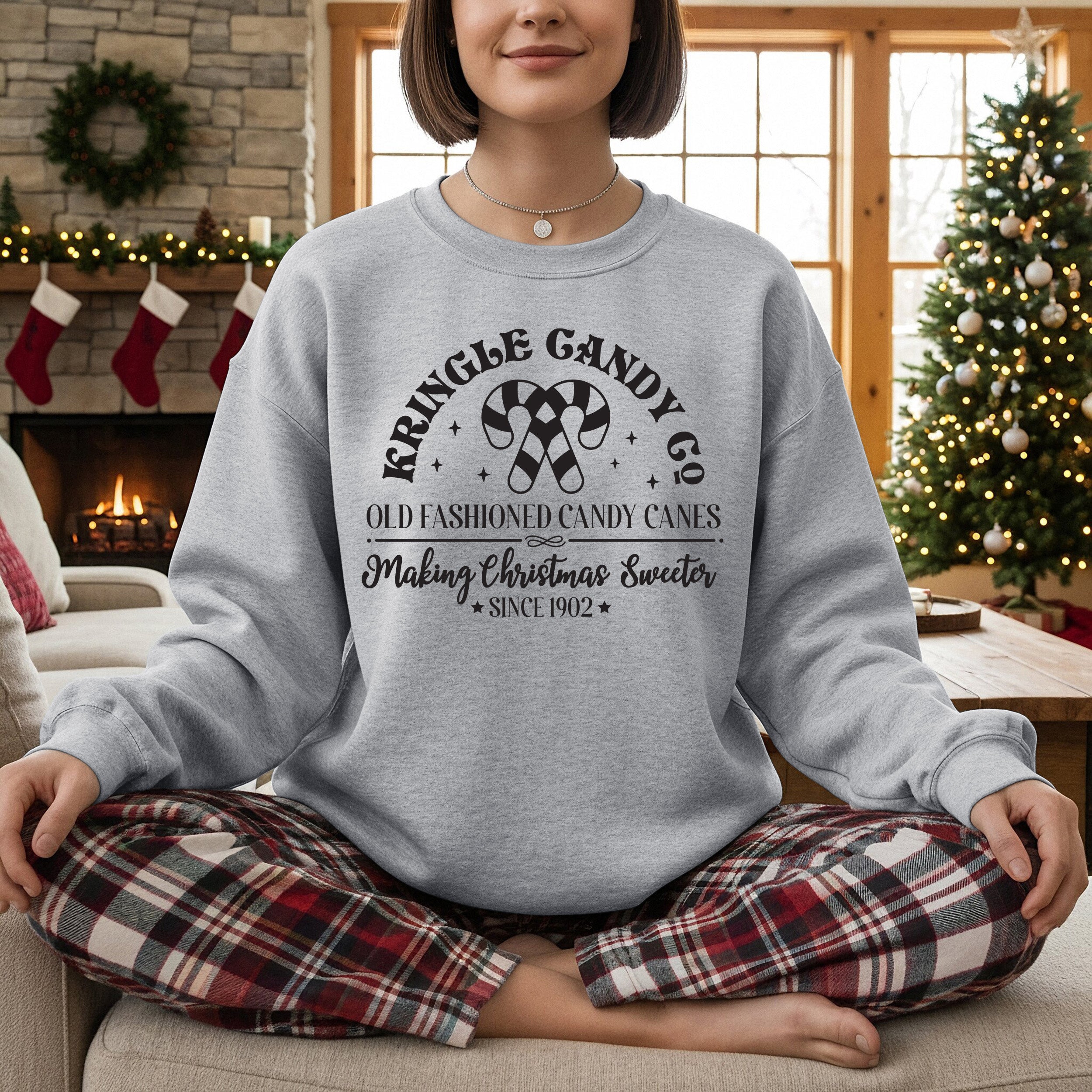 Person wearing a gray sweatshirt with Christmas-themed text in a festive living room.
